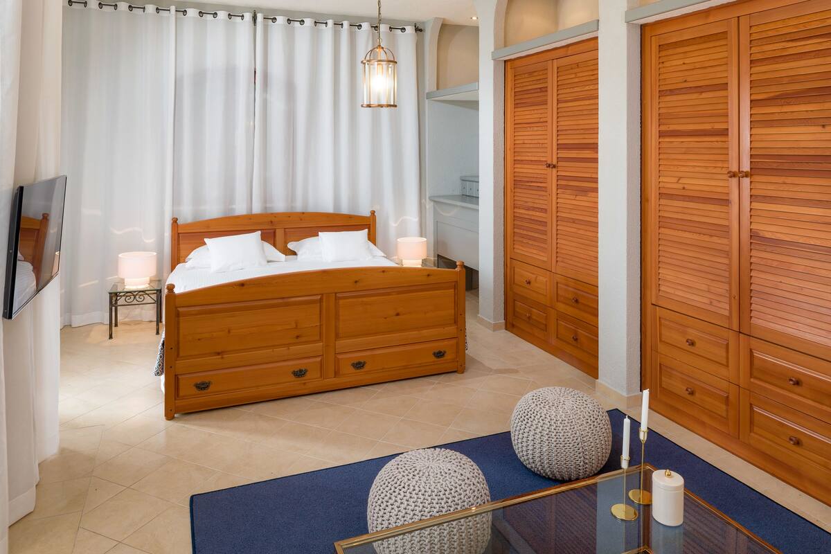 A bedroom with a wooden bed, a nightstand, a mirror, and a wardrobe.