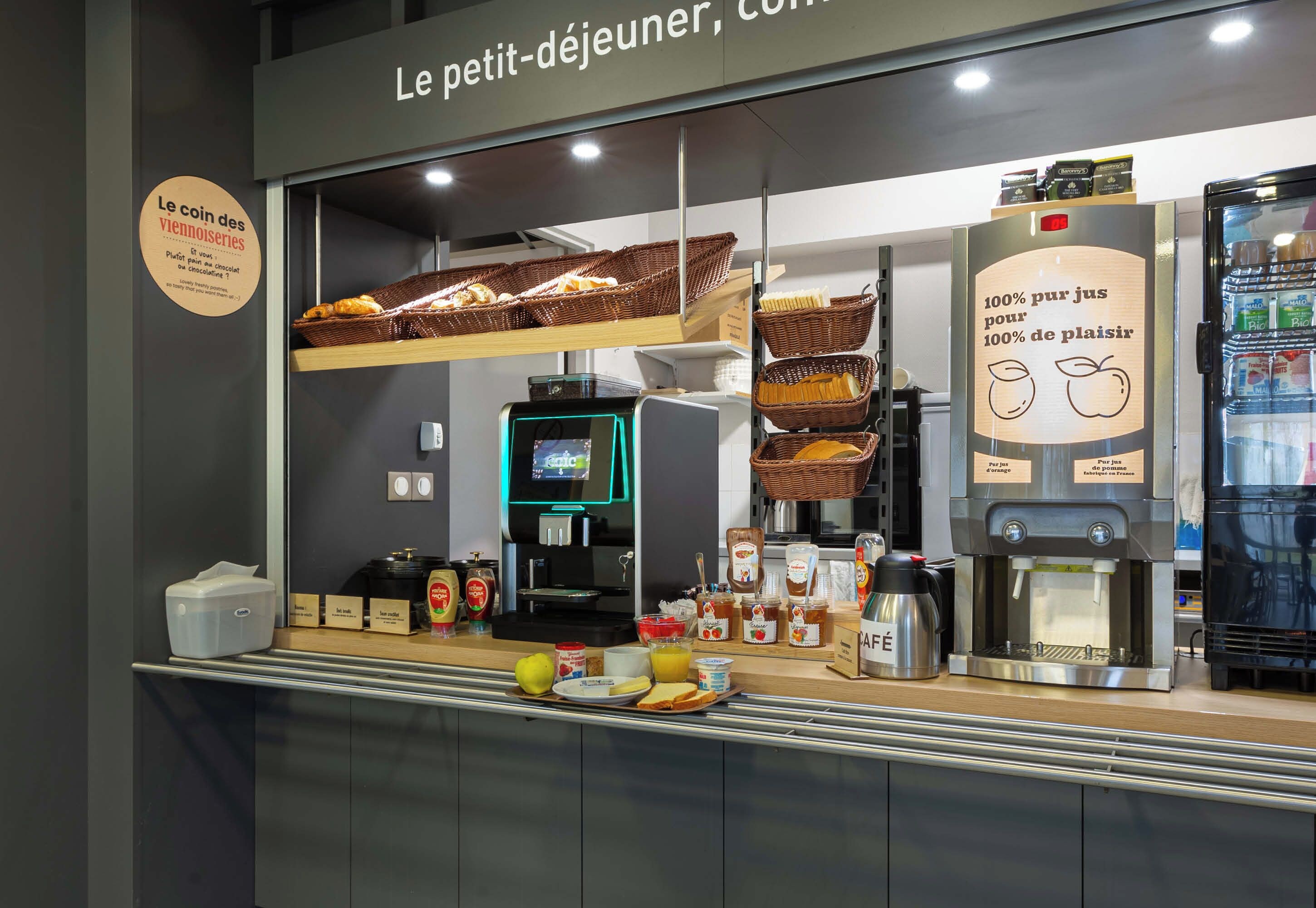 Una barra de desayuno con cestas de pan, una máquina de café y diversas opciones para el desayuno.