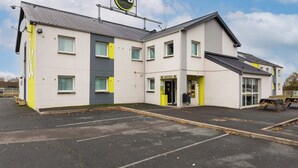 Een bed and breakfast hotel met modern design, met een opvallende ingang en een parkeerplaats.