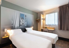 Habitación de hotel con dos camas, un escritorio, una silla, un cuadro en la pared y una ventana con cortinas.