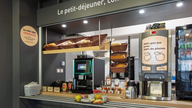 Een ontbijtbuffet met brodenmanden, een koffiemachine en diverse ontbijtartikelen.