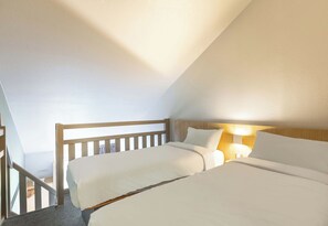 A bedroom with two beds, a wooden headboard, and a nightstand with a lamp. - B&B Hotel Bourges 2 (Bourges)