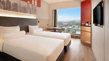 Une chambre d’hôtel avec deux lits, une vue sur la ville, une télévision et un bureau.