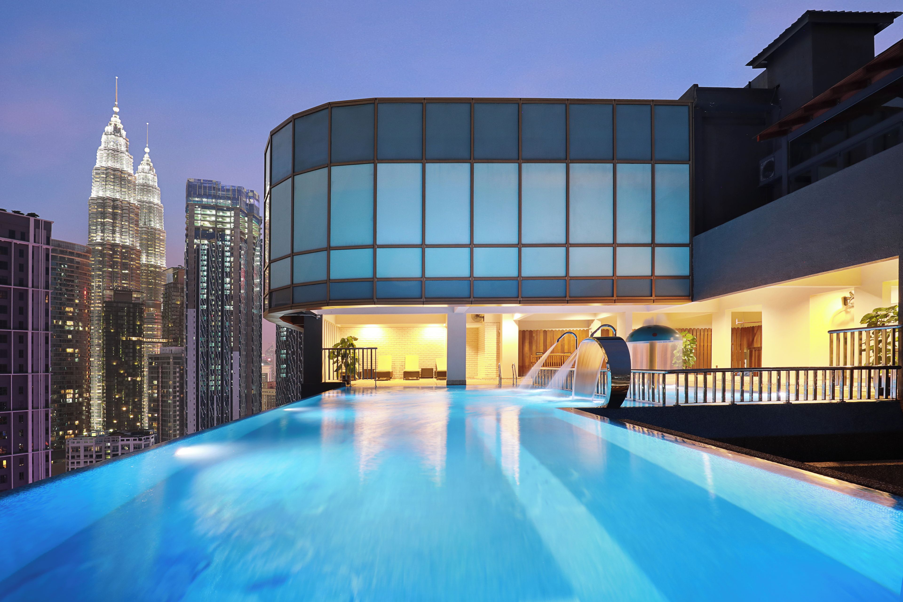 A modern building with a pool, featuring a glass facade and a view of the city skyline.