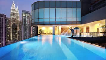A modern building with a pool, featuring a glass facade and a view of the city skyline.