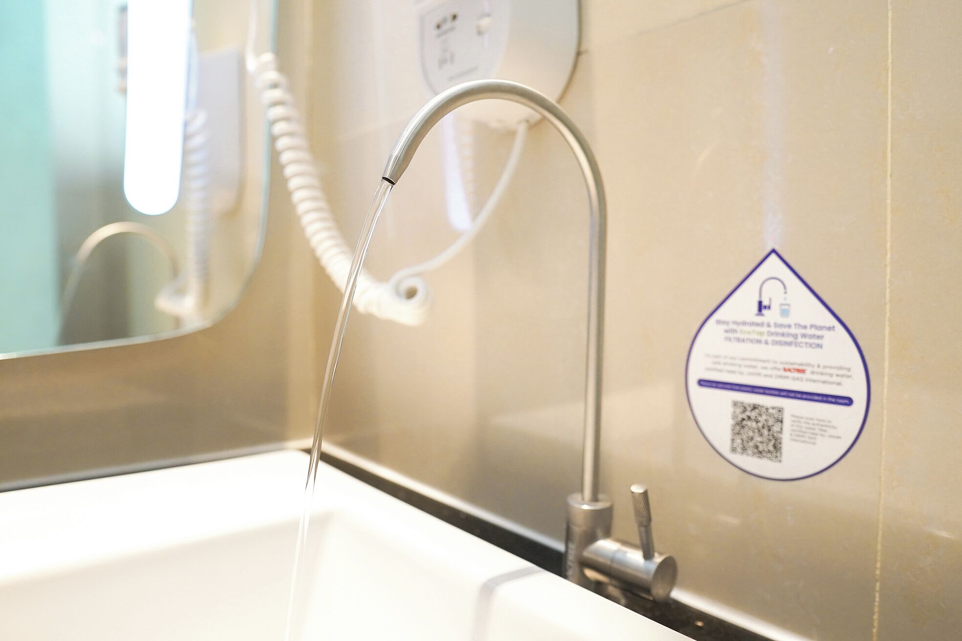 A bathroom sink with a faucet, a mirror, and a water conservation sign.