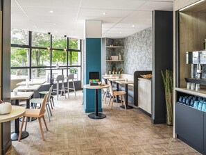 A modern cafe with wooden herringbone flooring, large windows, and a variety of seating arrangements including tables and booths. - ibis Styles Sceaux Paris Sud (Sceaux)
