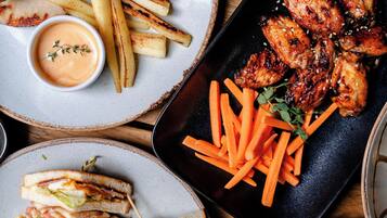 A meal with grilled chicken wings, fries, and a sandwich.