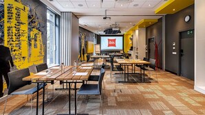 A modern conference room with a large screen, multiple tables, and chairs. - ibis Vilnius Centre (Vilnius)