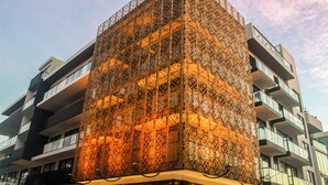 Ein modernes Gebäude mit einer einzigartigen Gitterfassade und mehreren Balkonen.