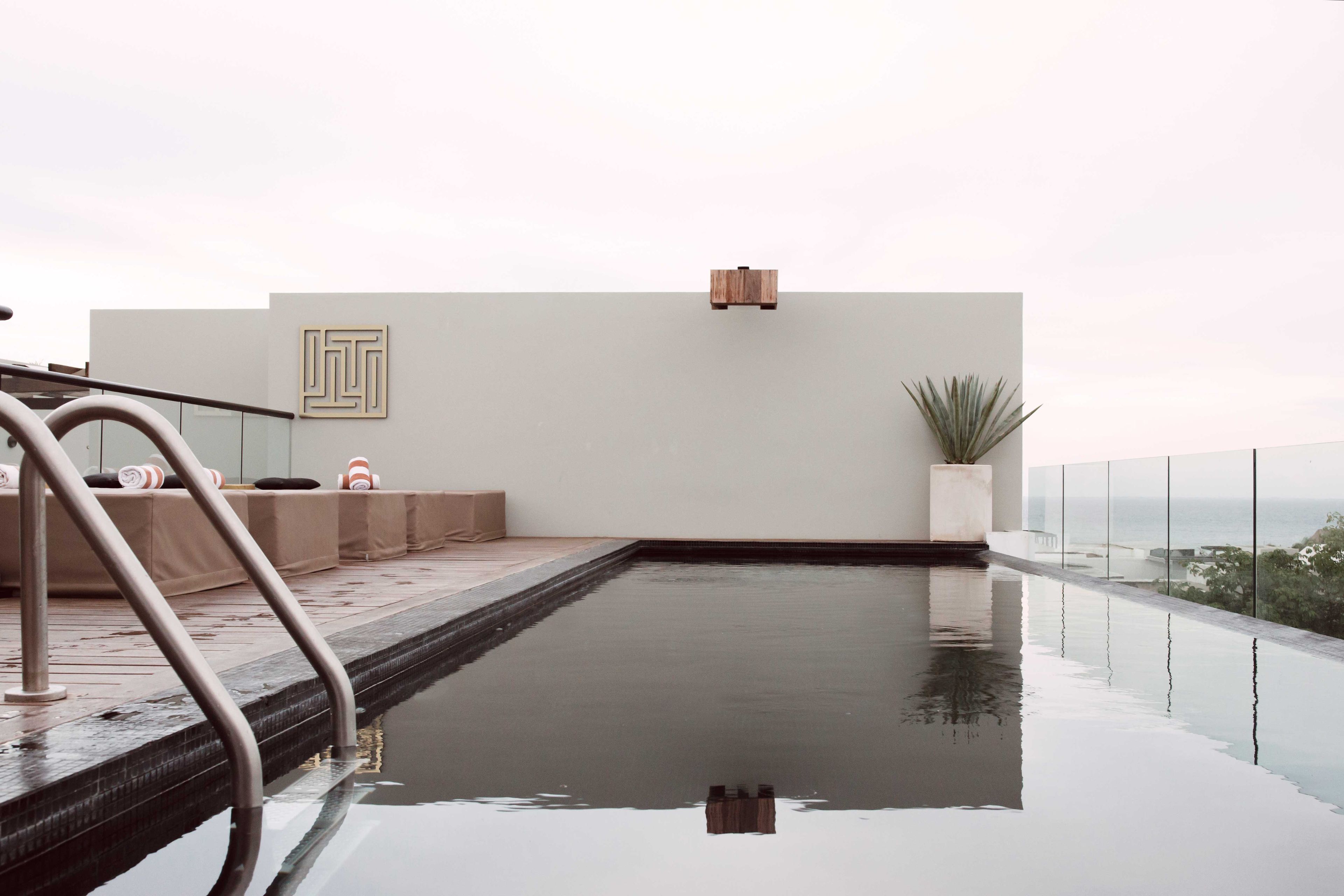 A modern infinity pool with a clear view of the horizon, a minimalist seating area, and a simple, clean design.