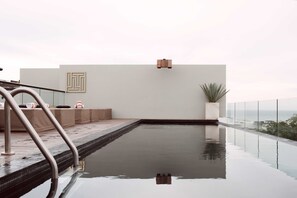 Una piscina infinita moderna con una vista despejada del horizonte, un área de descanso minimalista y un diseño sencillo y limpio.