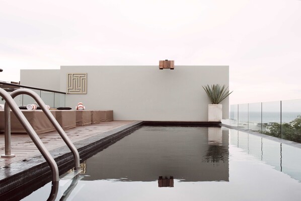 Ein moderner Infinity-Pool mit freiem Blick auf den Horizont, eine minimalistische Sitzgruppe und ein schlichtes, klares Design.