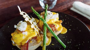 Un plat composé d’œufs, de bacon et d’asperges, servi dans une assiette noire.