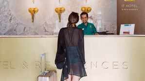 A hotel reception desk with a marble wall and mounted elephant head decorations. - IT Boutique Hotel & Restaurant (Playa del Carmen)