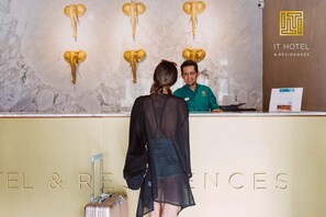 A hotel reception desk with a marble wall and mounted elephant head decorations. - IT Boutique Hotel & Restaurant (Playa del Carmen)