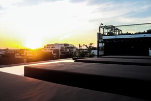 Une terrasse sur le toit offrant une vue sur le coucher de soleil et les bâtiments au loin.