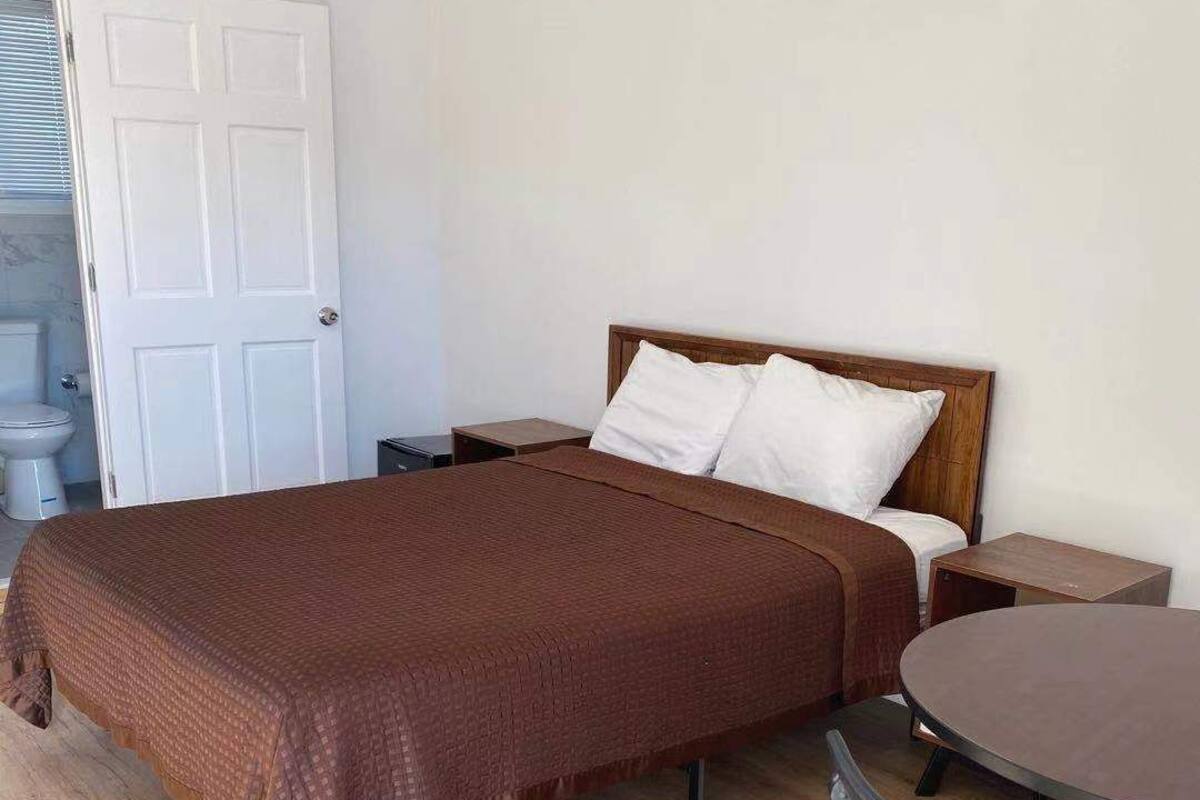 A bedroom with a large bed, a bedside table, a chair, and a round table.