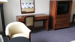 A hotel room with a wooden desk, a chair, a television, and a lamp. - Village Motel (Ellenville)
