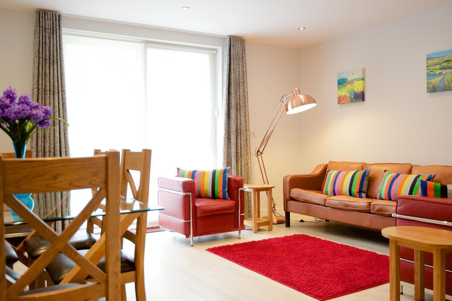 Una sala de estar moderna con un sofá rojo, una mesa de comedor de madera y una alfombra roja.