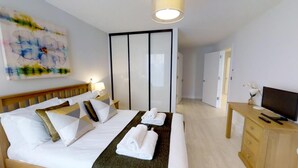 A hotel room with a bed, a desk, a TV, and a wardrobe. - Signet Apartments-Vesta (Cambridge)