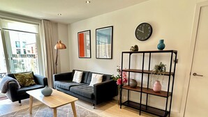 A modern living room with a sofa, coffee table, and a decorative shelf. - Signet Apartments-Vesta (Cambridge)