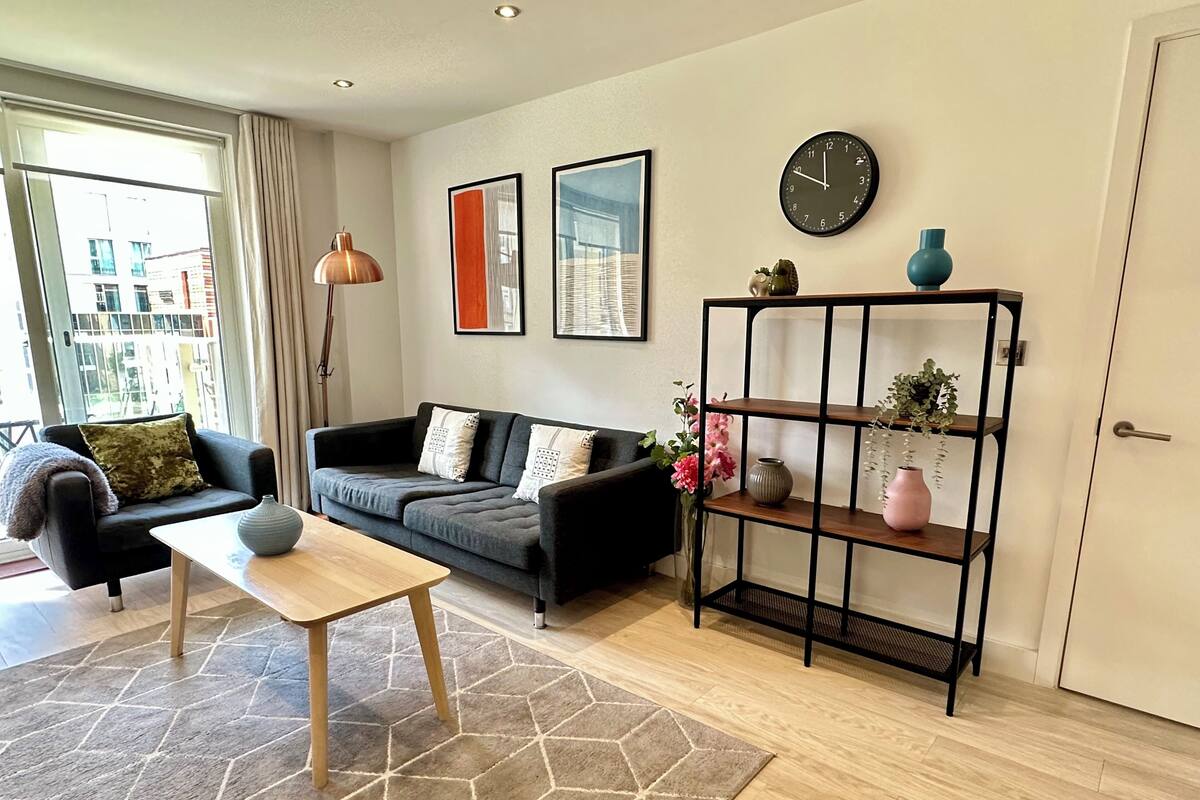 A modern living room with a sofa, coffee table, and a decorative shelf.