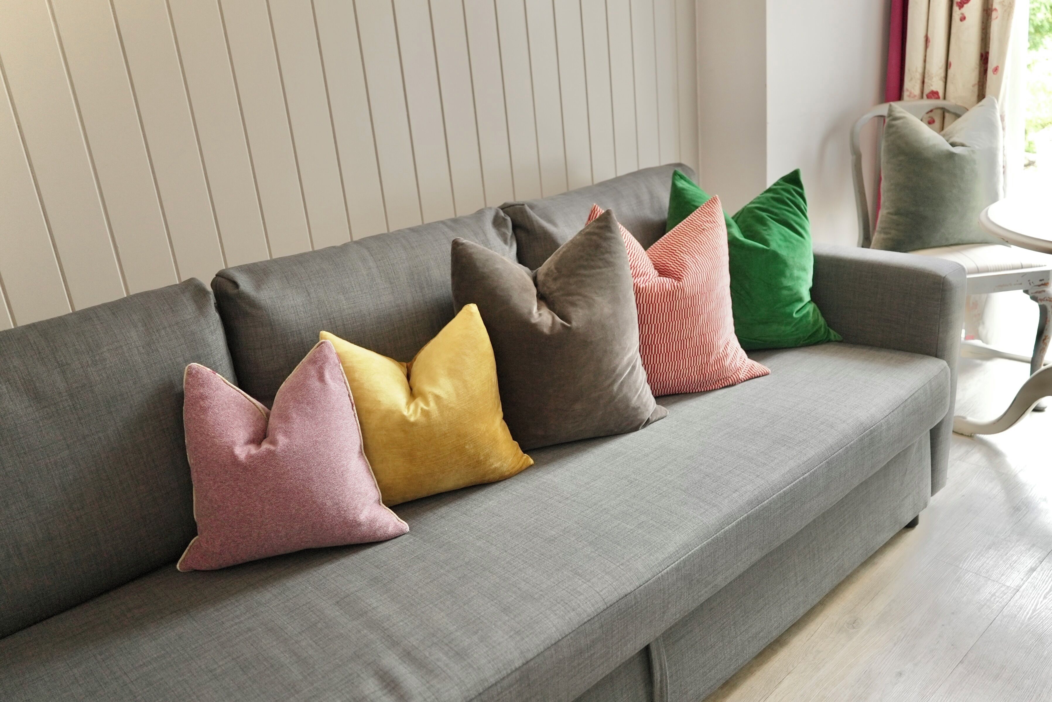A grey sofa with four cushions in various colors.