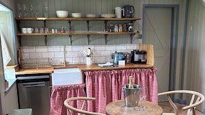 A kitchen with wooden shelves, a sink, and a dining area with a table and chairs.