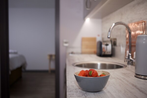 Une cuisine moderne avec un saladier de fraises sur le plan de travail, un évier et une machine à café.