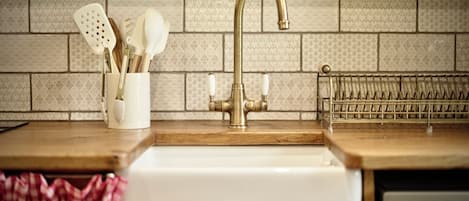 A kitchen with a sink, a faucet, and a utensil holder with spoons and spatulas.