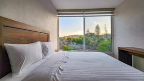 A bedroom with a large window, a wooden headboard, and a neatly made bed. - Gamma Chapala (Chapala)
