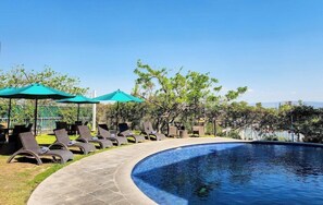 A poolside area with lounge chairs and umbrellas, surrounded by trees and a clear sky. - Gamma Chapala (Chapala)