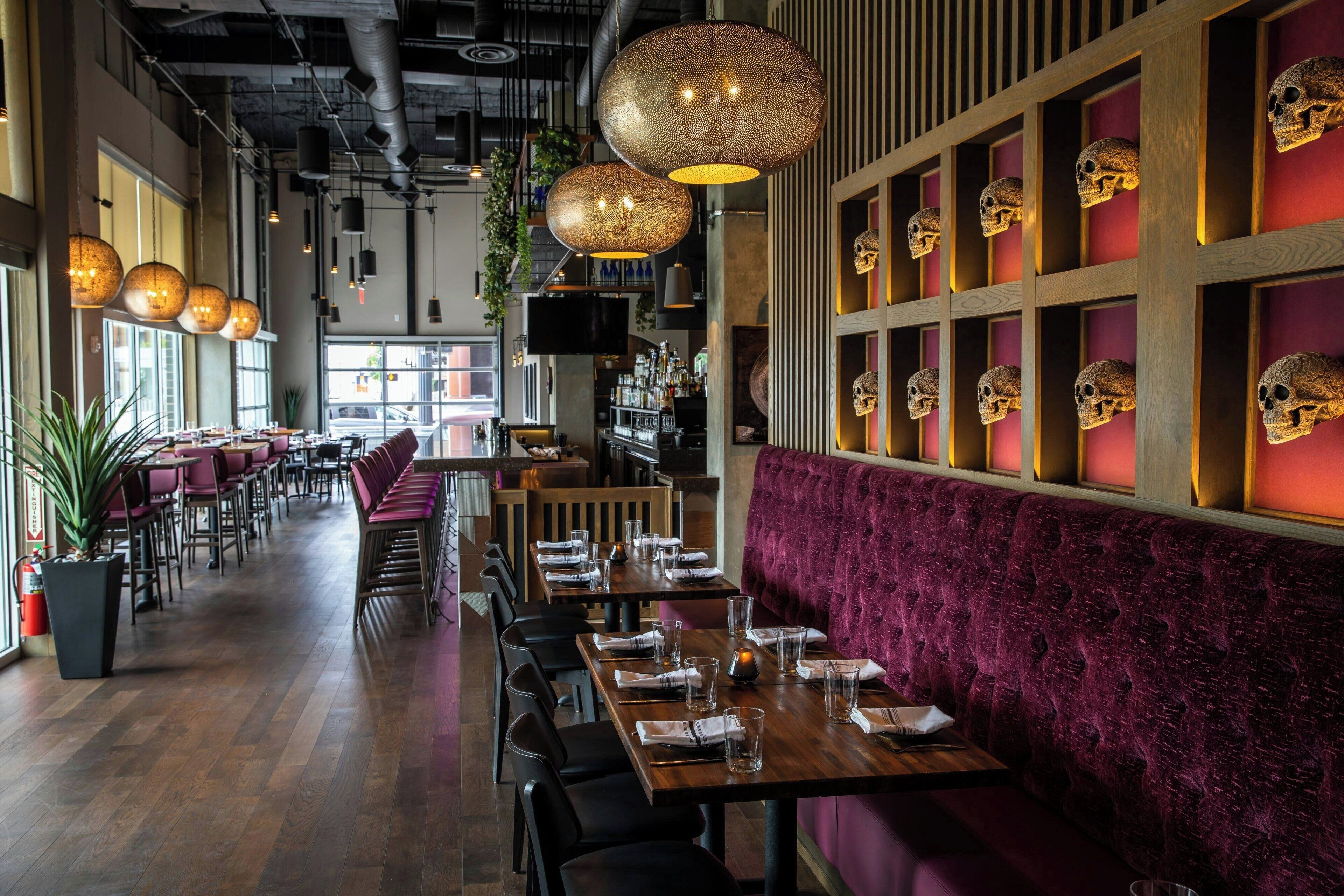 A restaurant with wooden tables, purple upholstered booths, and skull decorations on the wall.