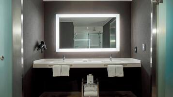 Un baño moderno con dos lavamanos, un espejo grande y un carrito pequeño con toallas.