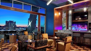 Zona de bar con asientos y vista a la ciudad.