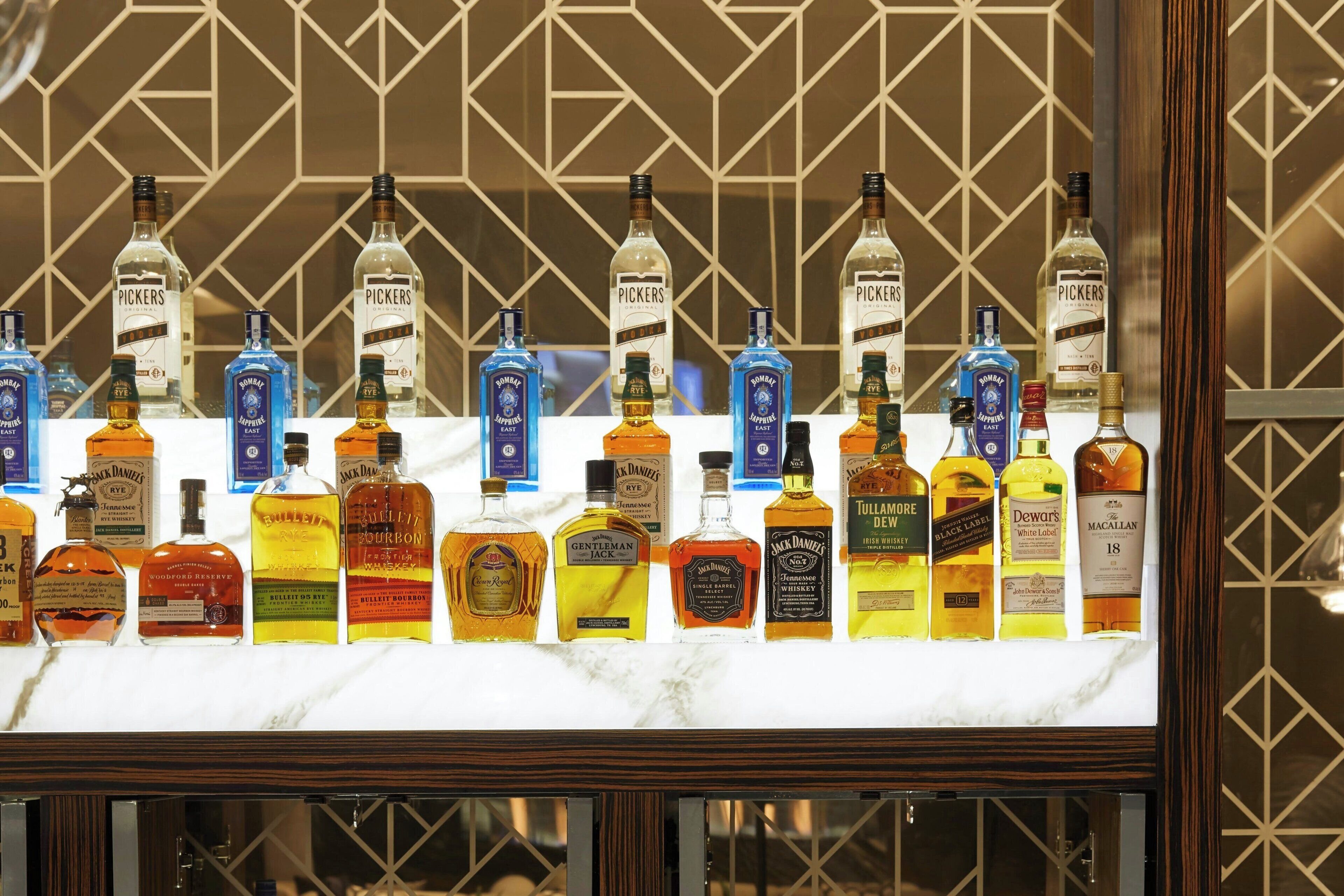 A bar with a variety of liquor bottles arranged on a marble countertop.
