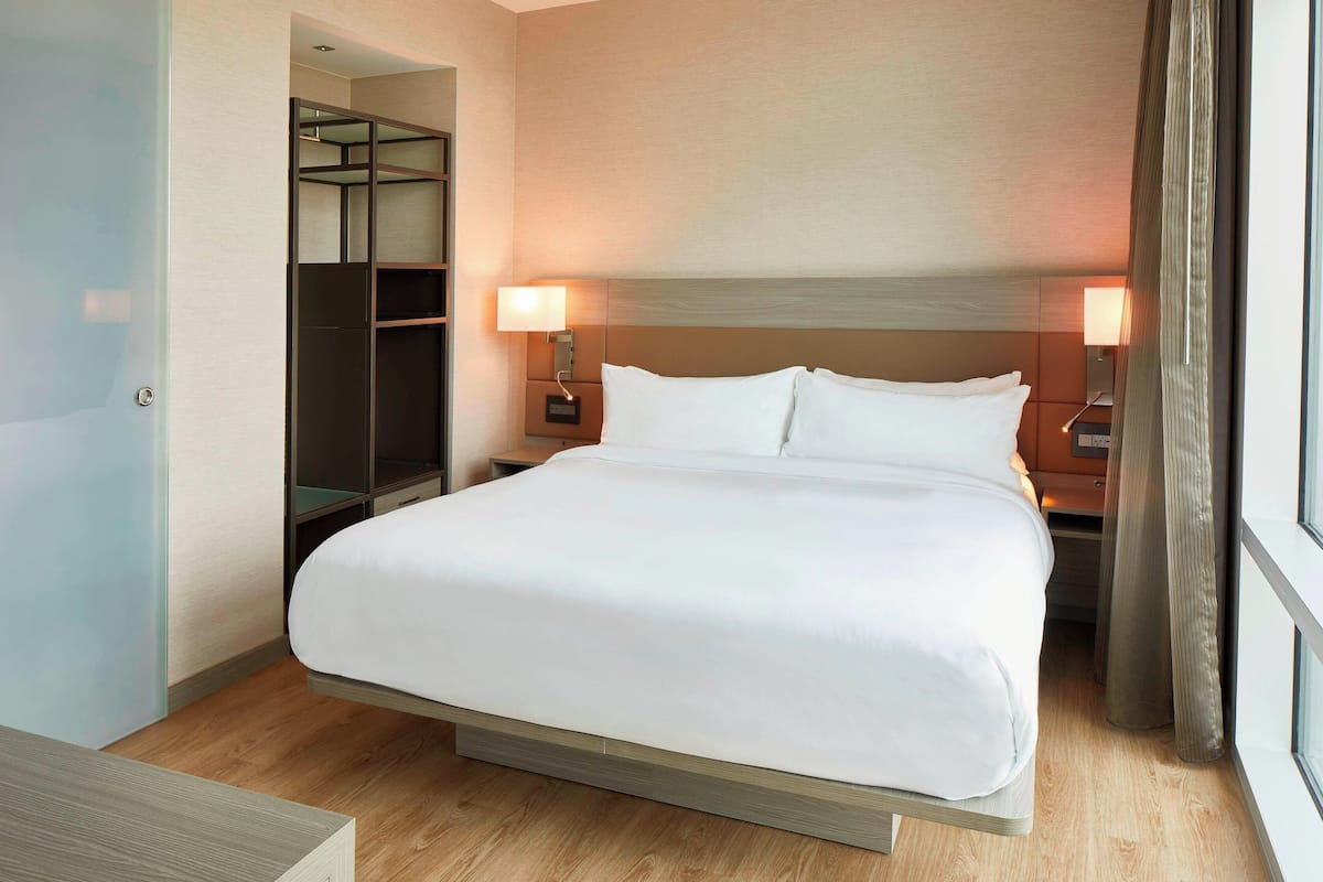 Ein Hotelzimmer mit einem großen Bett, Nachttischlampen, einem Kleiderschrank und einem Spiegel.
