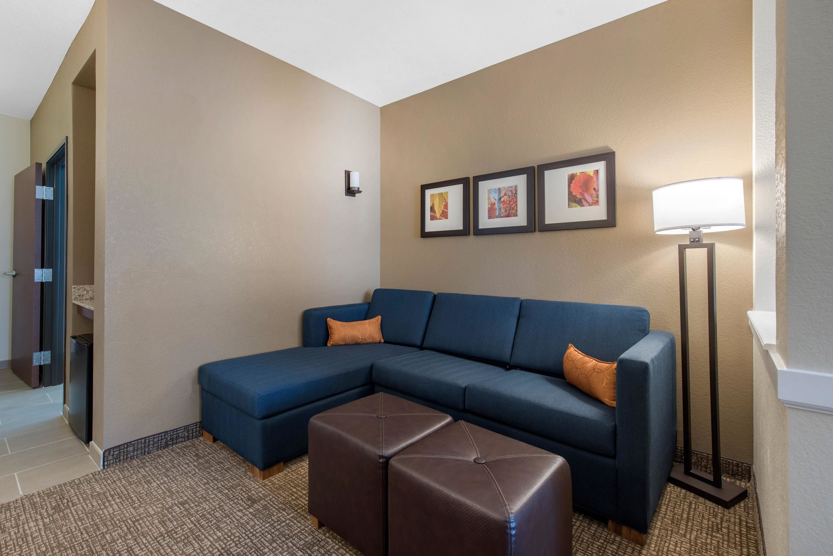 A modern living room with a sectional sofa, a brown ottoman, and a floor lamp.