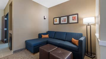 A modern living room with a sectional sofa, a brown ottoman, and a floor lamp.