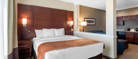 Ein Hotelzimmer mit einem großen Bett, Nachttischen, einem Schreibtisch und einer Küchenzeile.