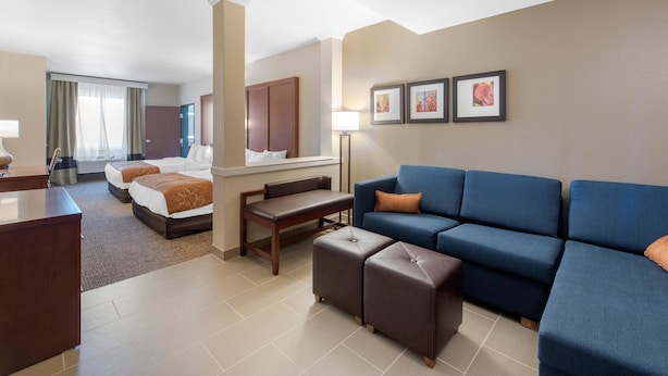 Habitación de hotel con dos camas, un sofá, un escritorio y una mesita de café.