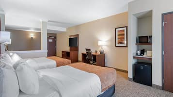 A hotel room with two beds, a desk, a chair, a TV, a lamp, a microwave, and a refrigerator.