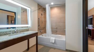 Un baño moderno con lavamanos de encimera de granito, bañera y ducha con cortina.