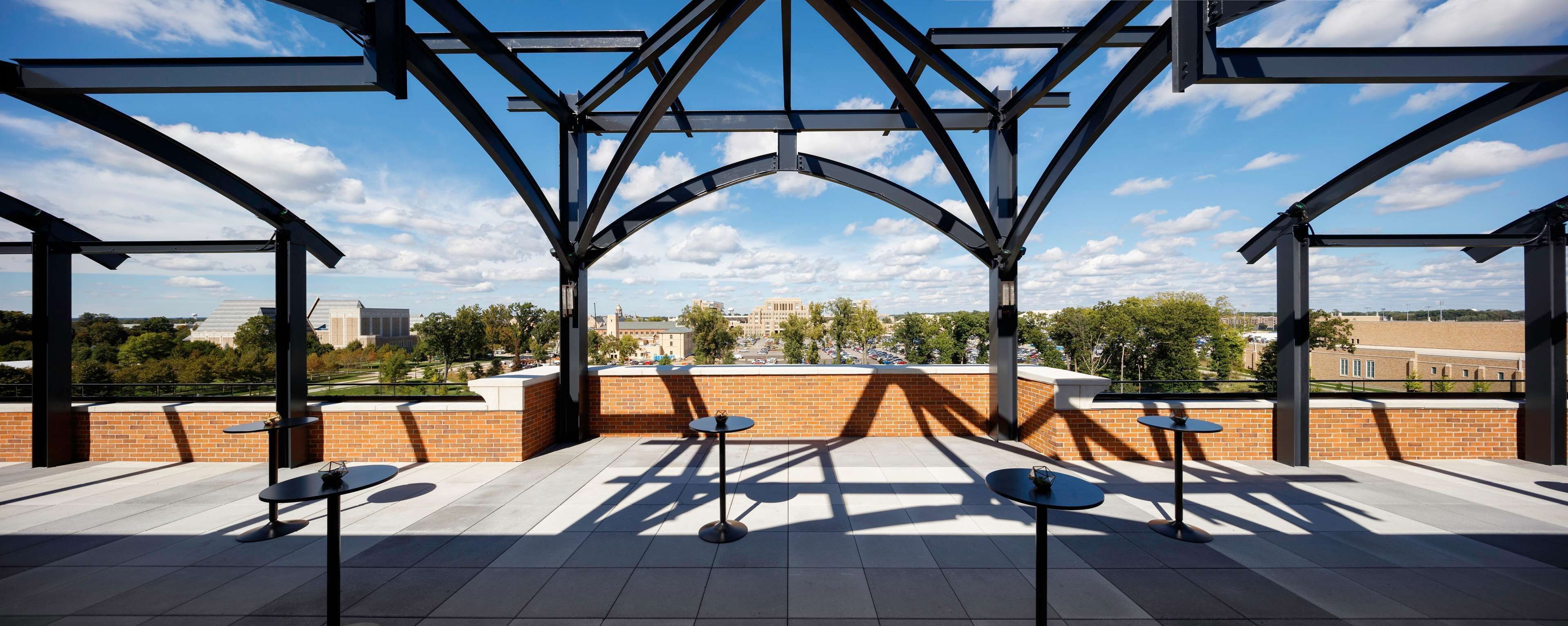 An outdoor terrace with a metal framework, brick walls, and tiled flooring.