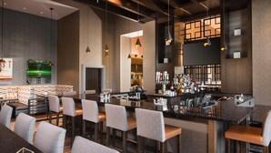 Un espace bar moderne avec des tabourets hauts, un comptoir et une variété de bouteilles et de verres.