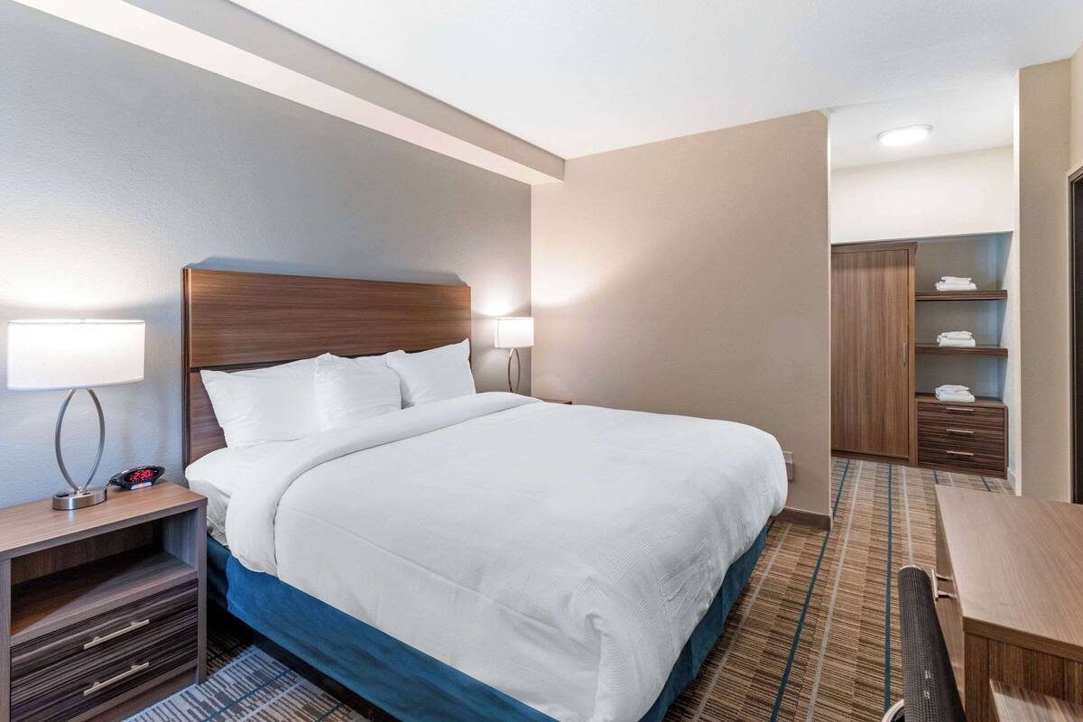 A hotel room with a large bed, bedside lamps, a desk, and a wardrobe.