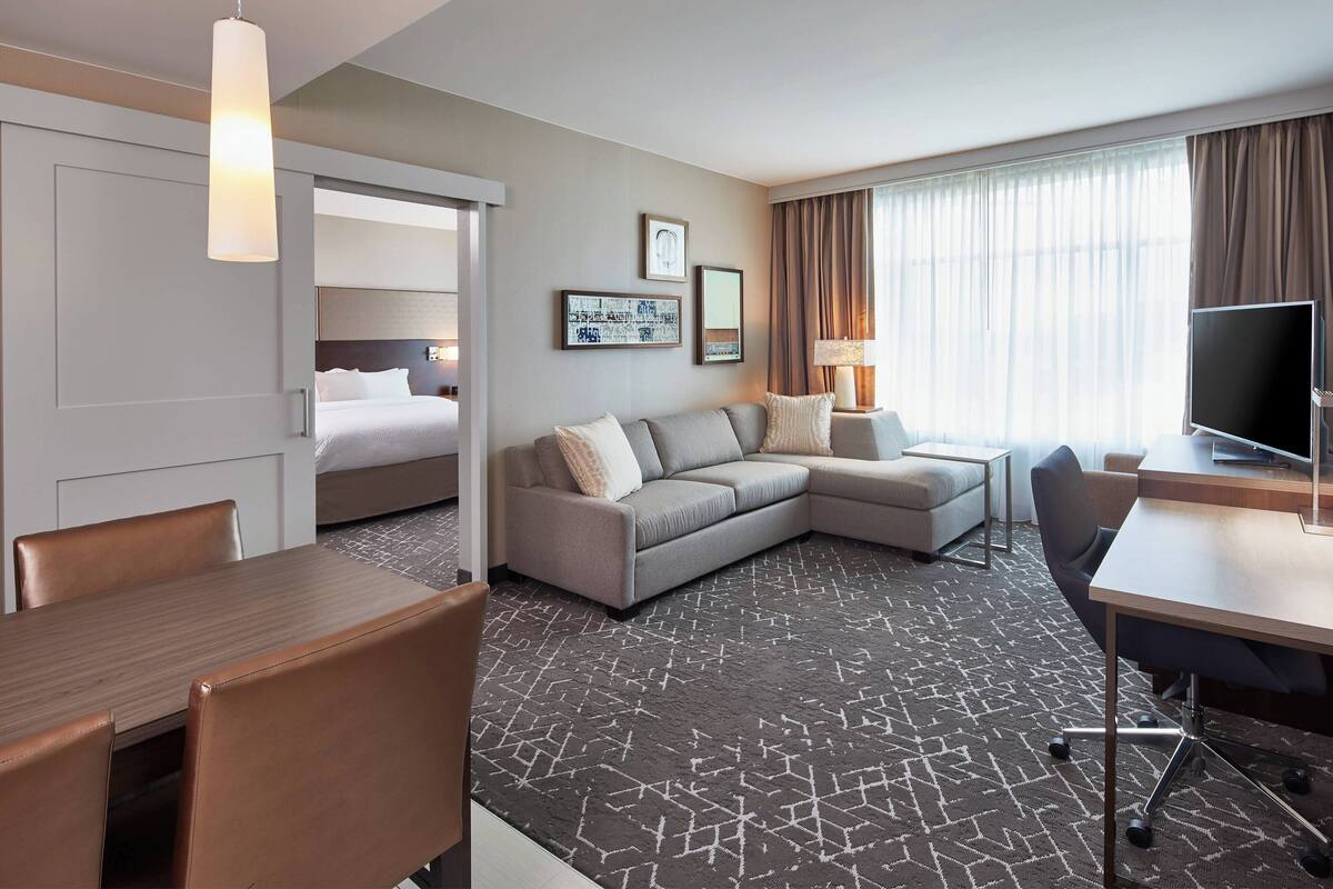 Una habitación de hotel con una cama, un sofá, un escritorio y un televisor.