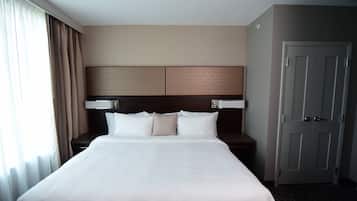 A hotel room with a large bed, a headboard, a nightstand, and a door.