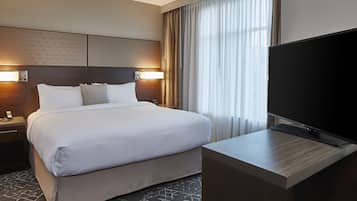 A hotel room with a large bed, a flat-screen TV, and a desk.